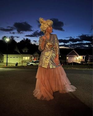Image of Marisol dresses as champaign bottle for halloween with pink dress and metallic jacket against black sky