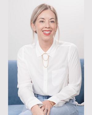 Marisol in white button up sitting for interview on blue couch